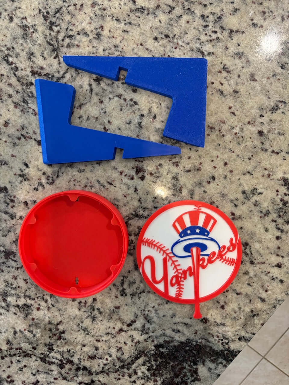 3D printed New York Yankees logo plaque pieces in blue and red on a granite surface, perfect for baseball decor.