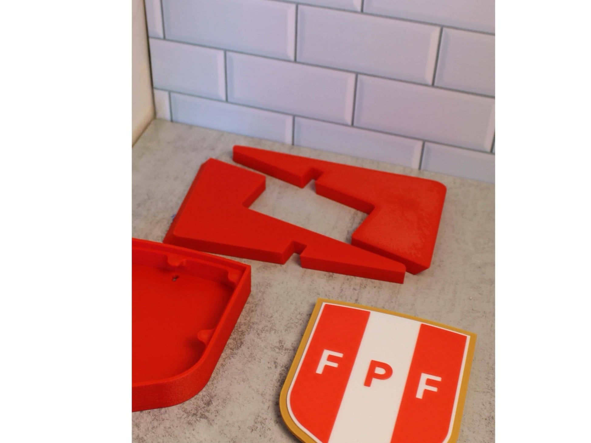 3D printed Peruvian Football Federation plaque pieces in vibrant red, showcasing high-quality materials and unique design.