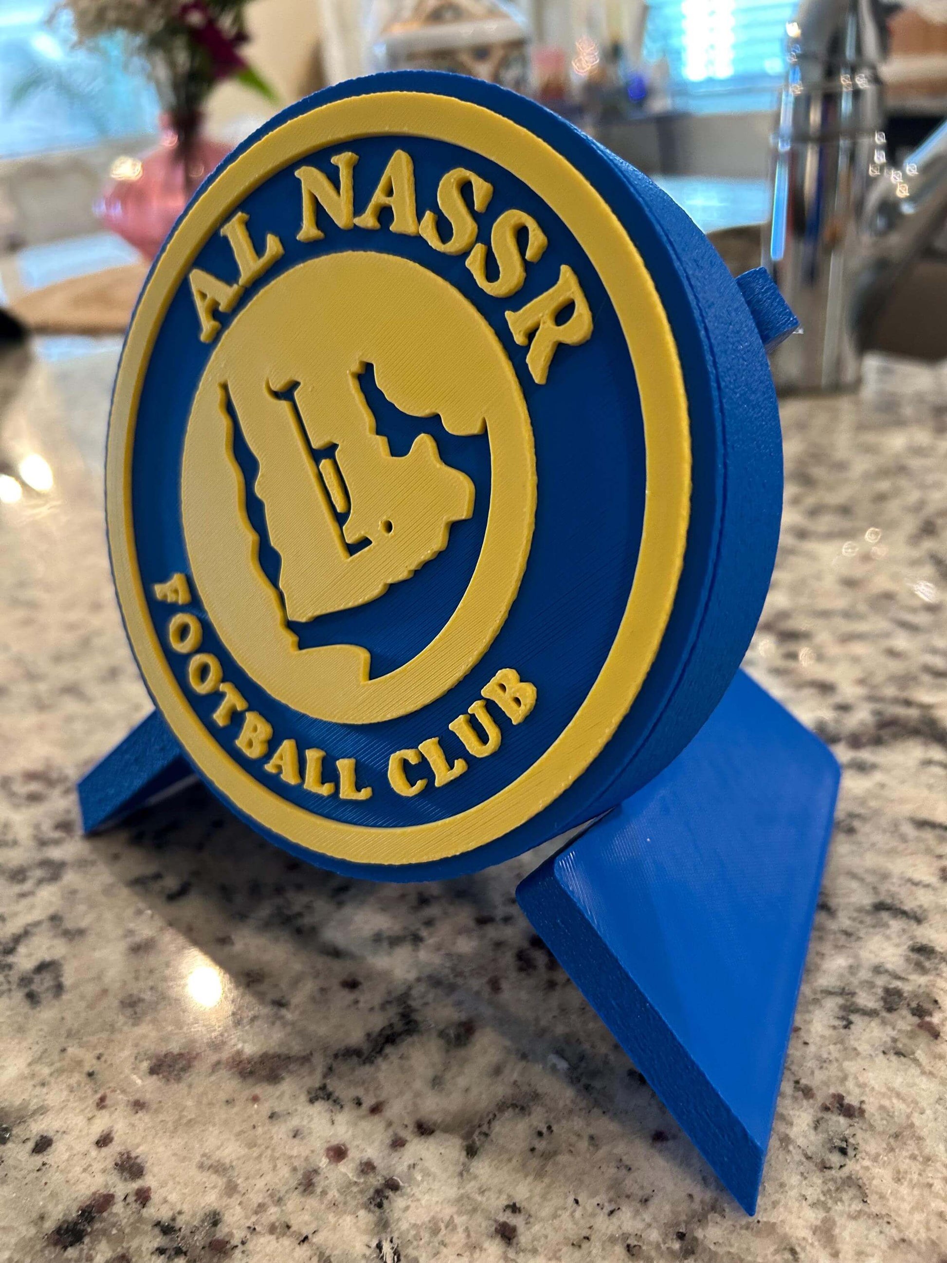 3D printed Al Nassr FC plaque in blue and yellow, showcasing the football club logo on a stylish stand.