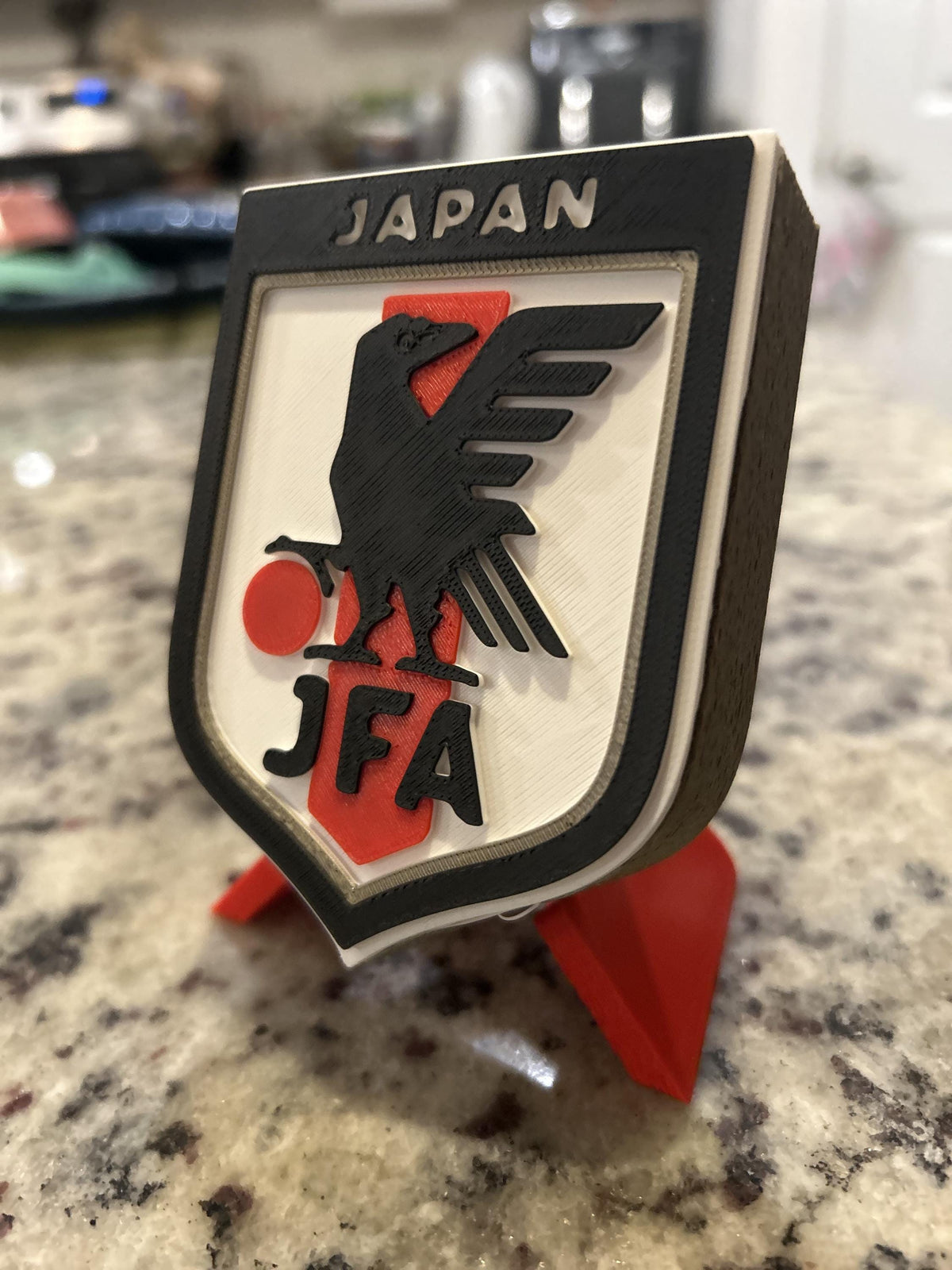 Japan JFA 3D printed shield crest display with red stand and hidden stash box, Samurai Blue soccer fan gift, made in USA
