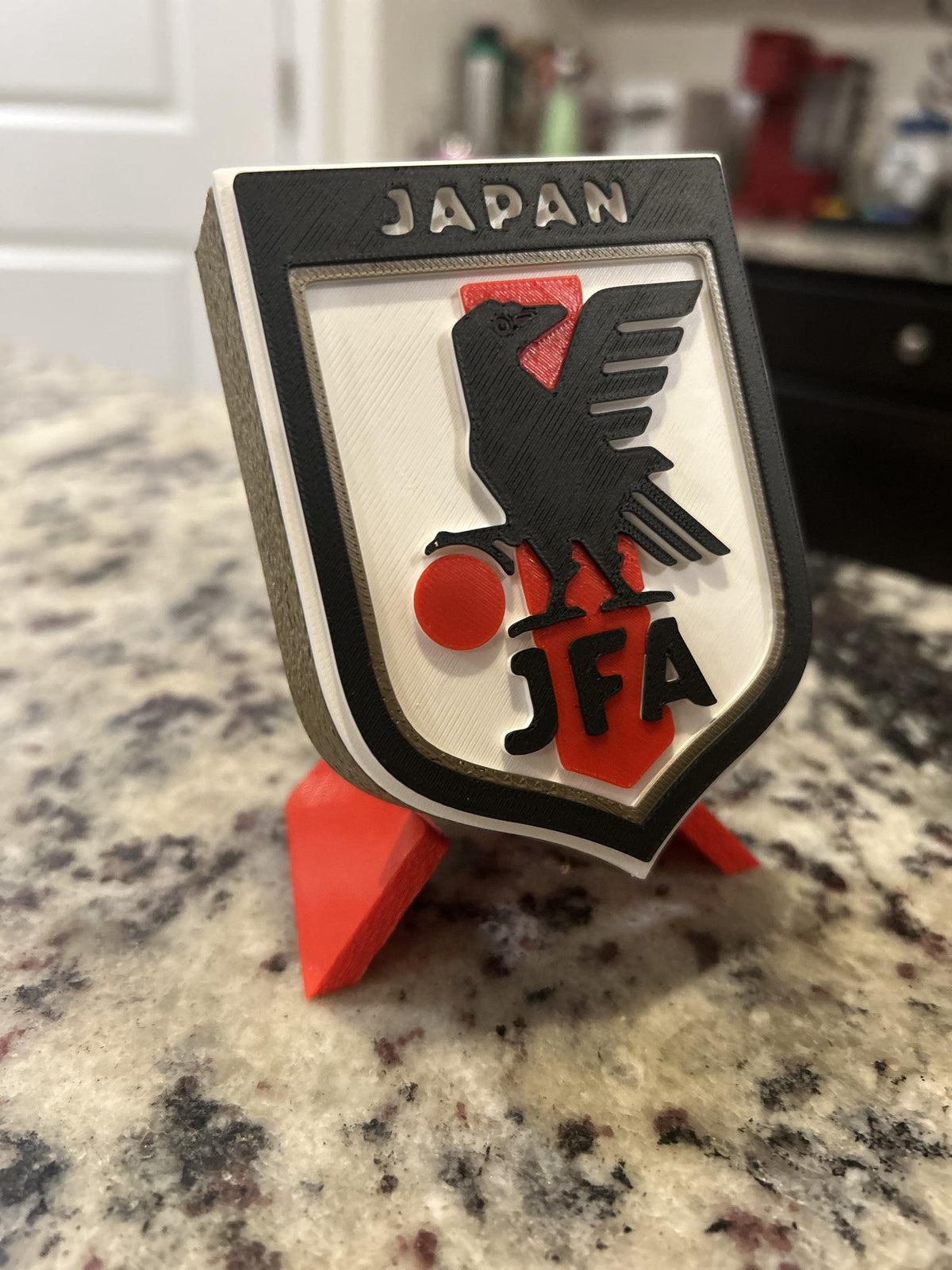 Japan JFA 3D printed shield crest display with red stand and hidden stash box, Samurai Blue soccer fan gift, made in USA