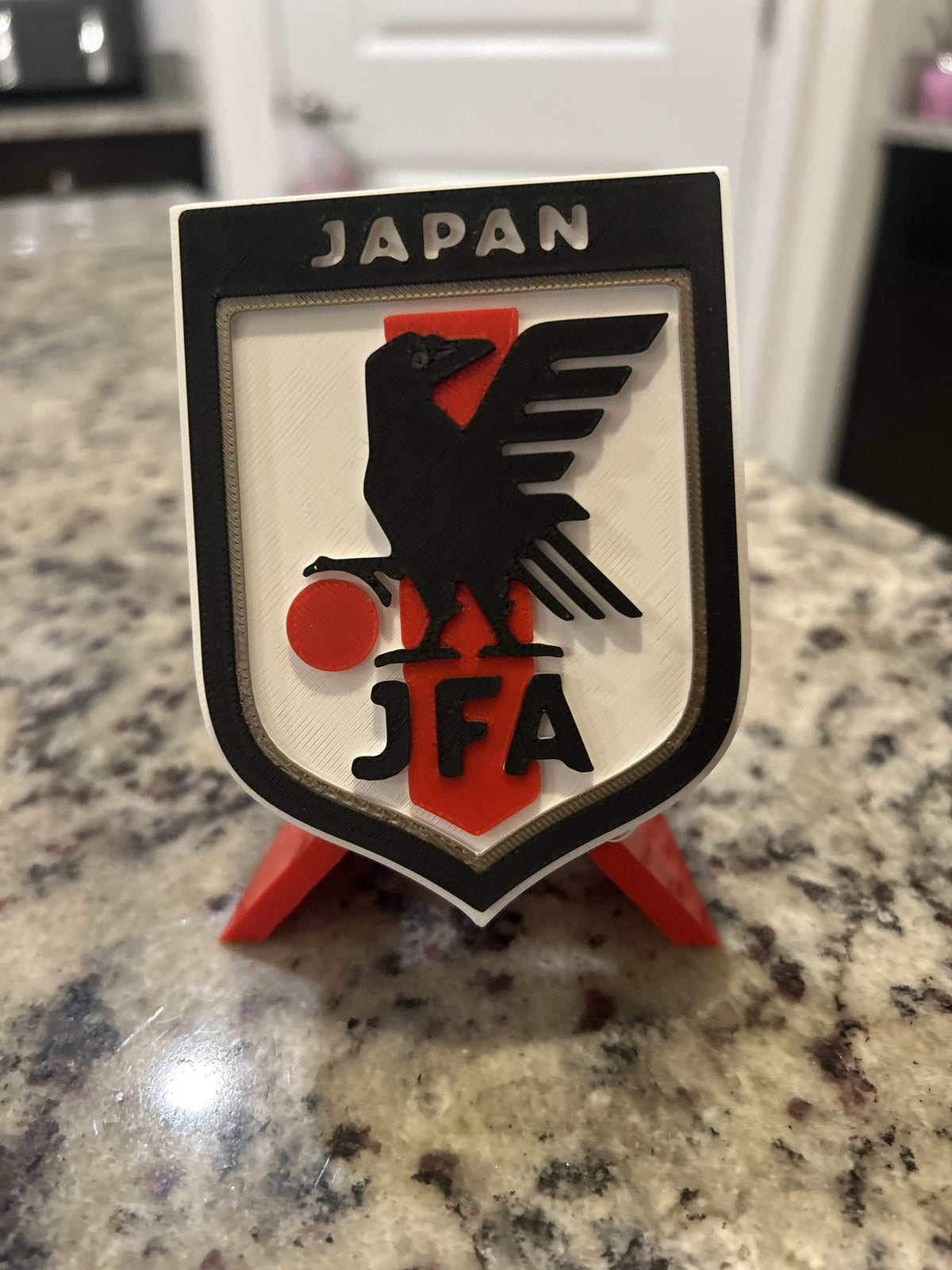 Japan JFA 3D printed shield crest display with red stand and hidden stash box, Samurai Blue soccer fan gift, made in USA