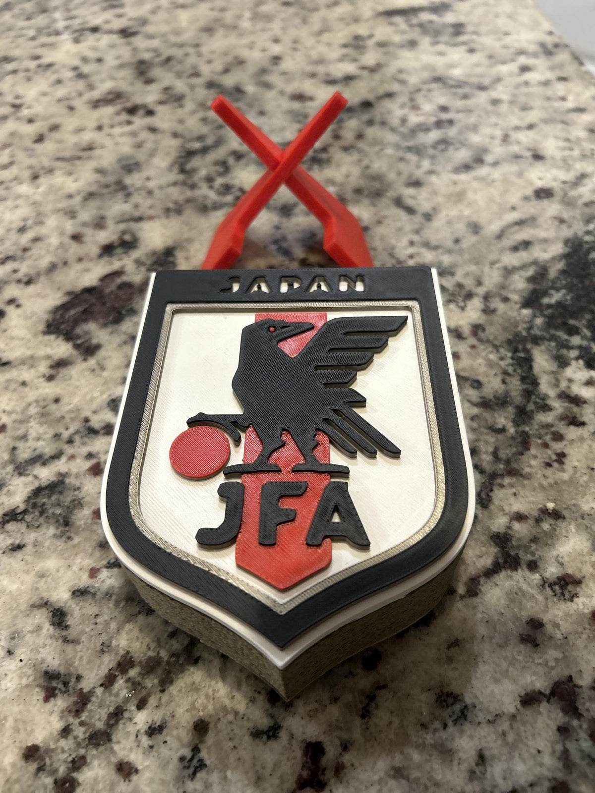 Japan JFA 3D printed shield crest display with red stand and hidden stash box, Samurai Blue soccer fan gift, made in USA