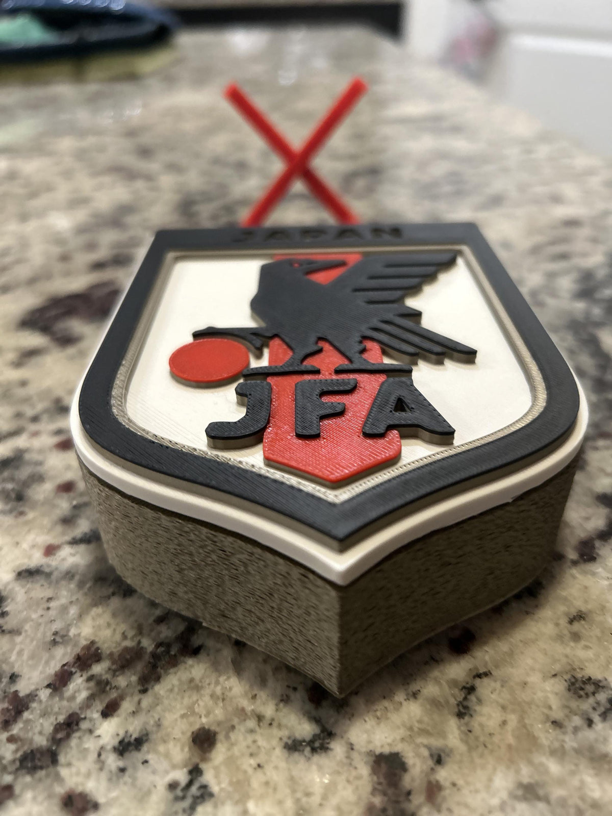 Japan JFA 3D printed shield crest display with red stand and hidden stash box, Samurai Blue soccer fan gift, made in USA