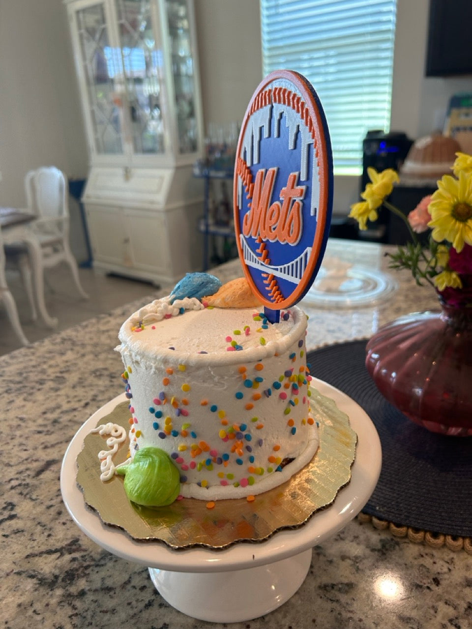 Mets birthday cake with the 3D-printed Mets topper on a white pedestal — angled lifestyle view