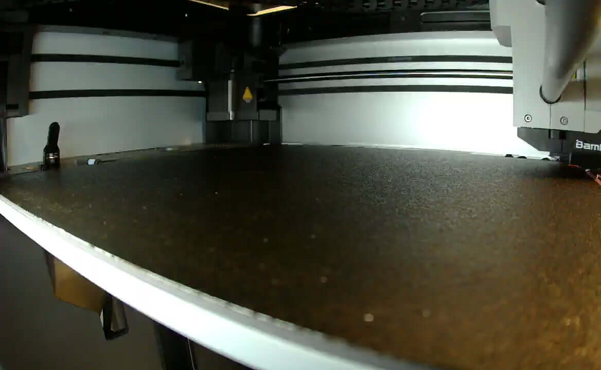 Load video: 3D printer in action on a sleek printing bed, showcasing precision for high-quality vibrant color creations.